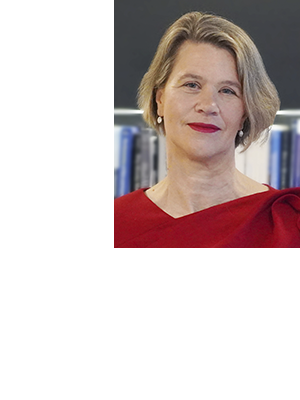 Jane Magill wears a red shirt, smiling against an office background.