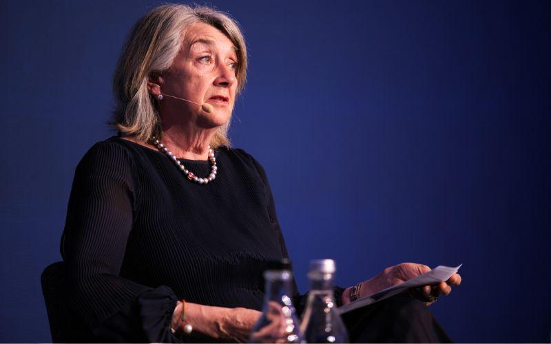 APRA Deputy Chair Margaret Cole delivering a speech against a dark blue background.